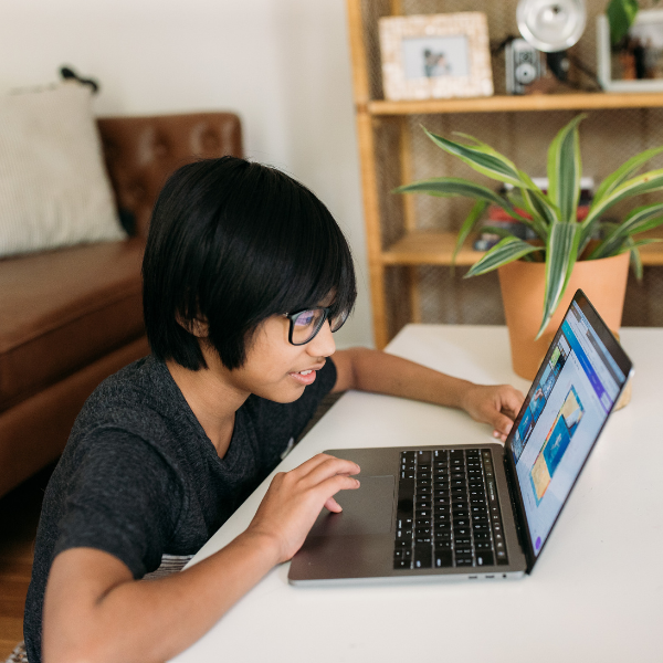 Child sitting at a desk and using a laptop.