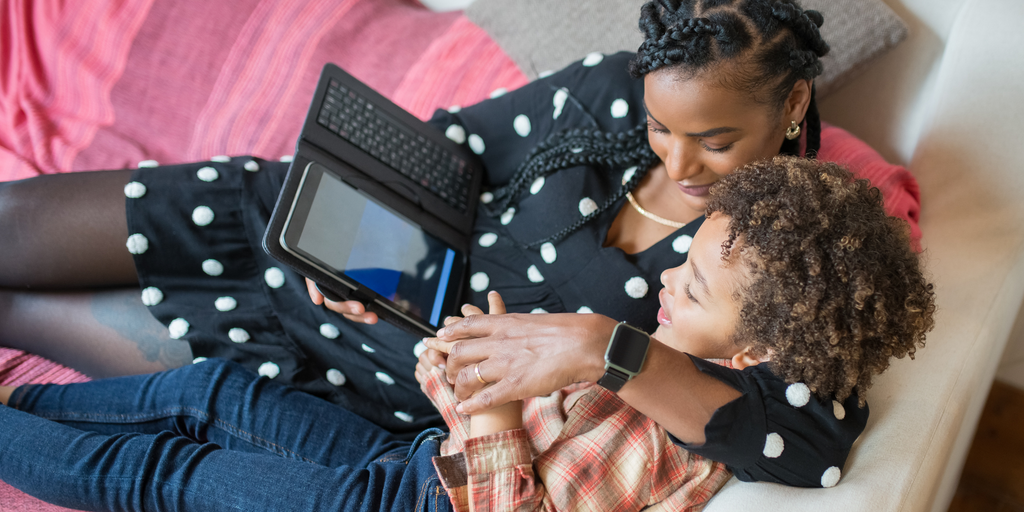 Parent and child sitting on a couch using an ipad together.